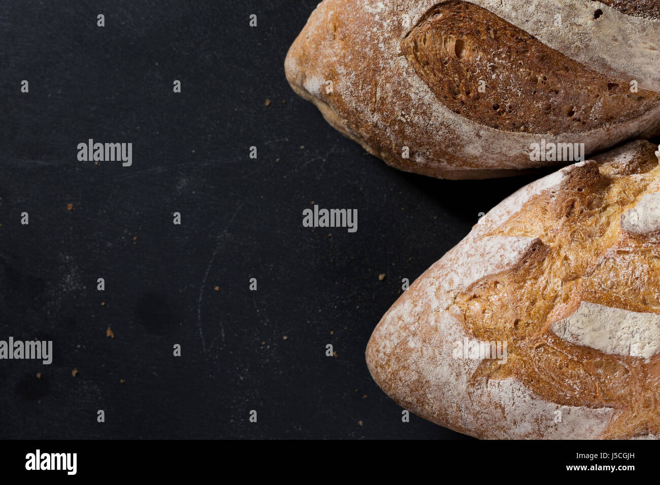 Rustic bread loaf on Black Slate Board. Stock Photo