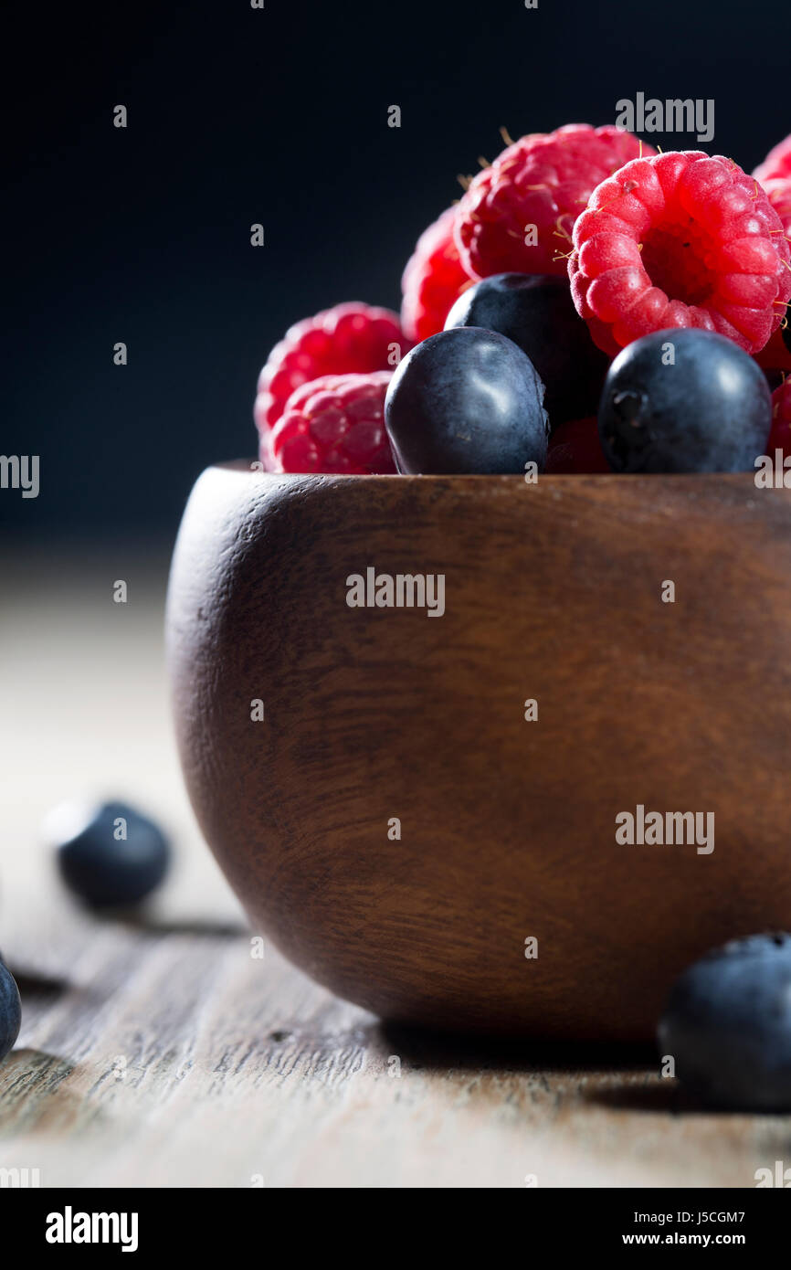 Bowl of fresh berries sitting on a rustic wooden table. Stock Photo