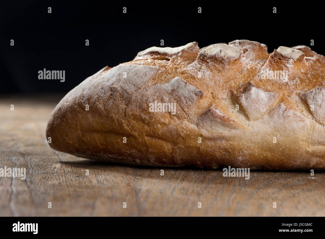 Close up view of a rustic loaf of bread on an old wooden table Stock ...