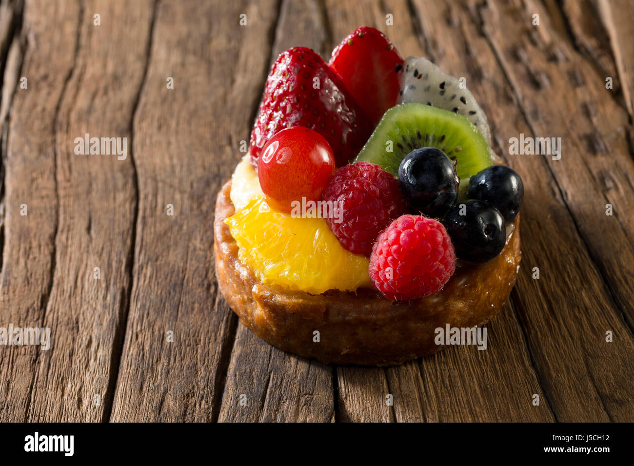 Fresh Fruit Flan sitting on a rustic wooden table. Stock Photo