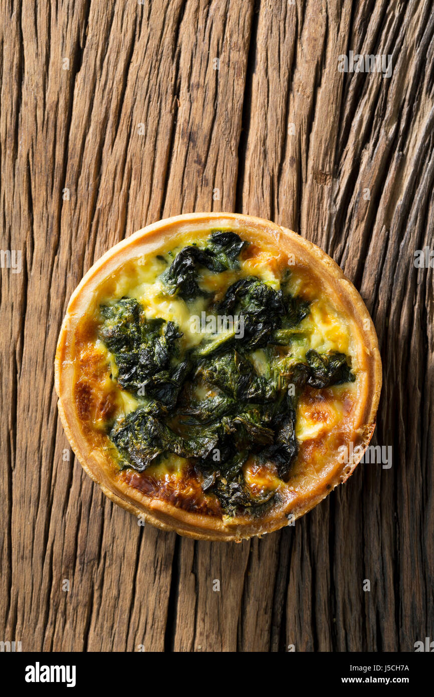Homemade Spinach quiche. The food is sitting on a rustic wooden background. Stock Photo