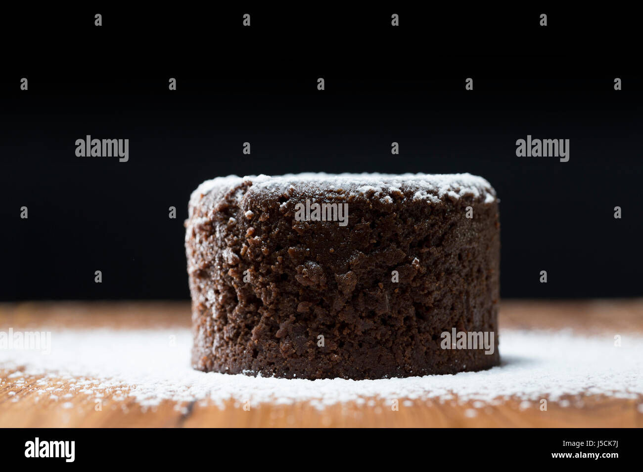 Chocolate Lava Cake with icing sugar. Chocolate pudding sitting on a rustic wooden table. Stock Photo