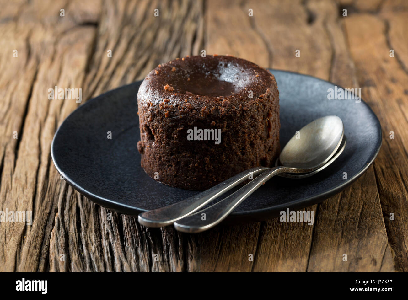 Homemade Chocolate Lava Cake. Chocolate pudding sitting on a rustic wooden table. Stock Photo