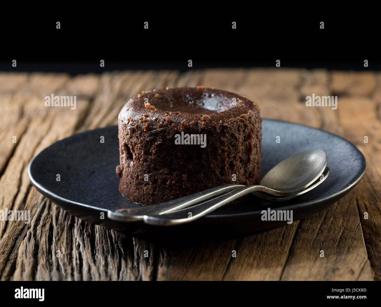 Homemade Chocolate Lava Cake. Chocolate pudding sitting on a rustic wooden table. Stock Photo