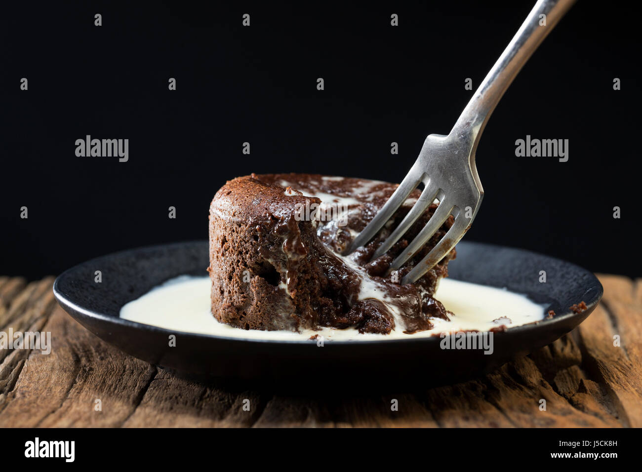 Chocolate Lava Cake and fresh cream. Chocolate pudding sitting on a rustic wooden table. Stock Photo