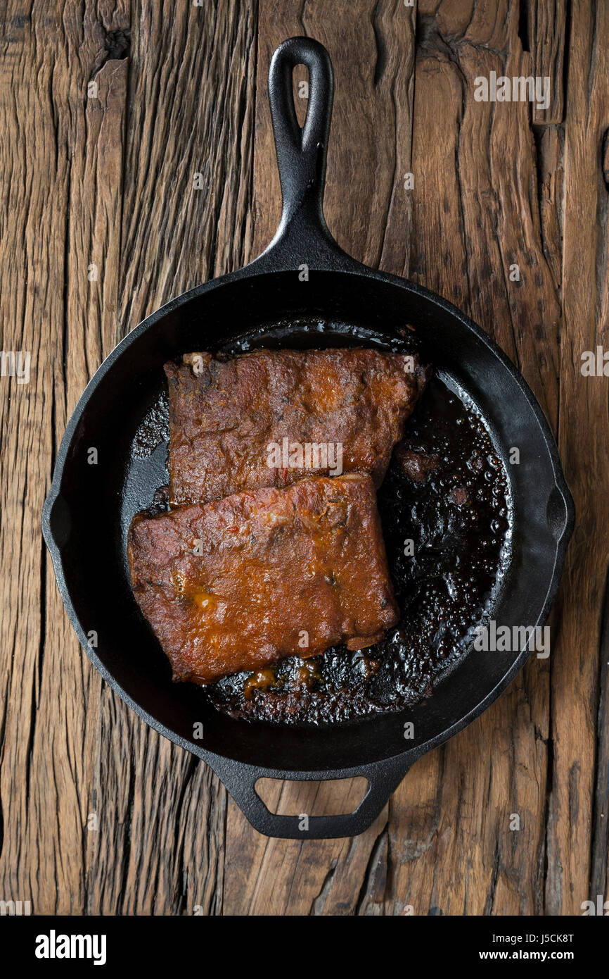 Roasted pork ribs in Barbecued sauce sitting on a rustic wooden table. Stock Photo