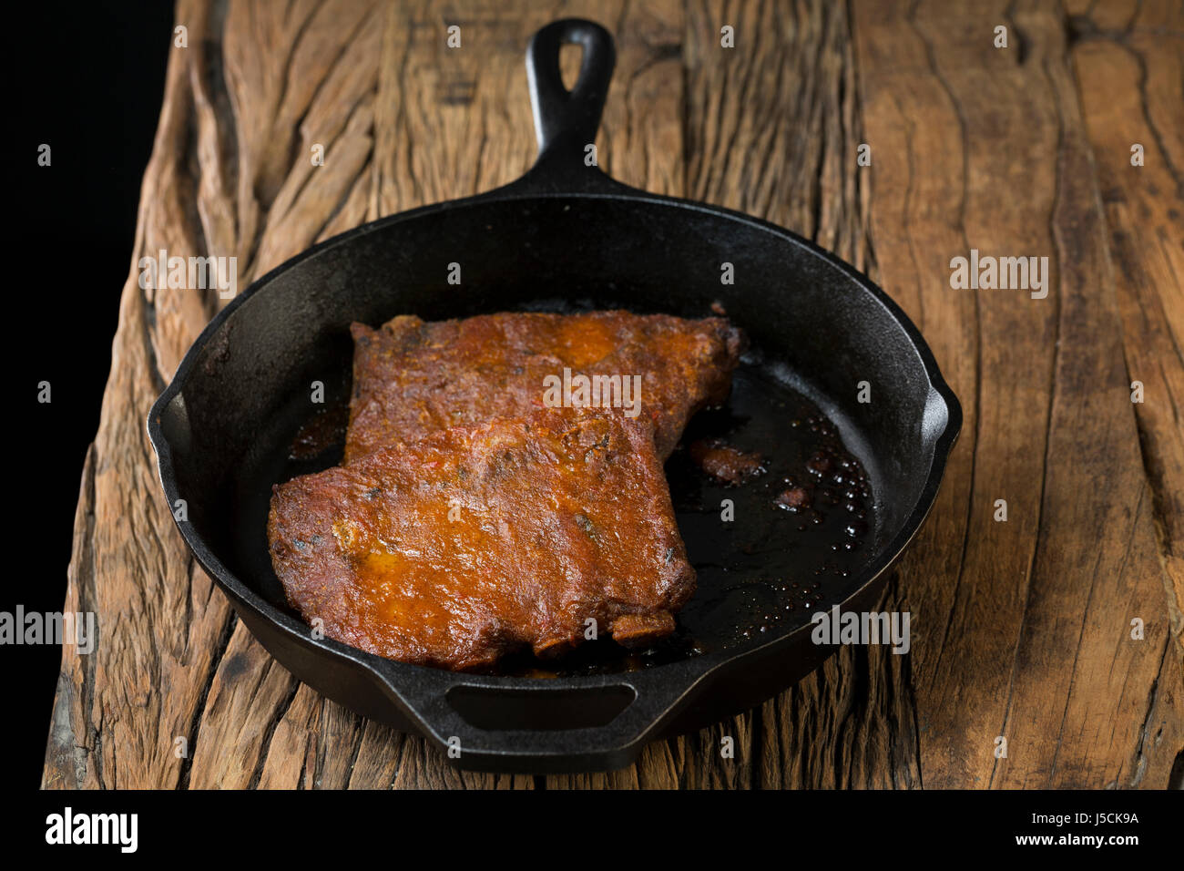 Roasted pork ribs in Barbecued sauce sitting on a rustic wooden table. Stock Photo