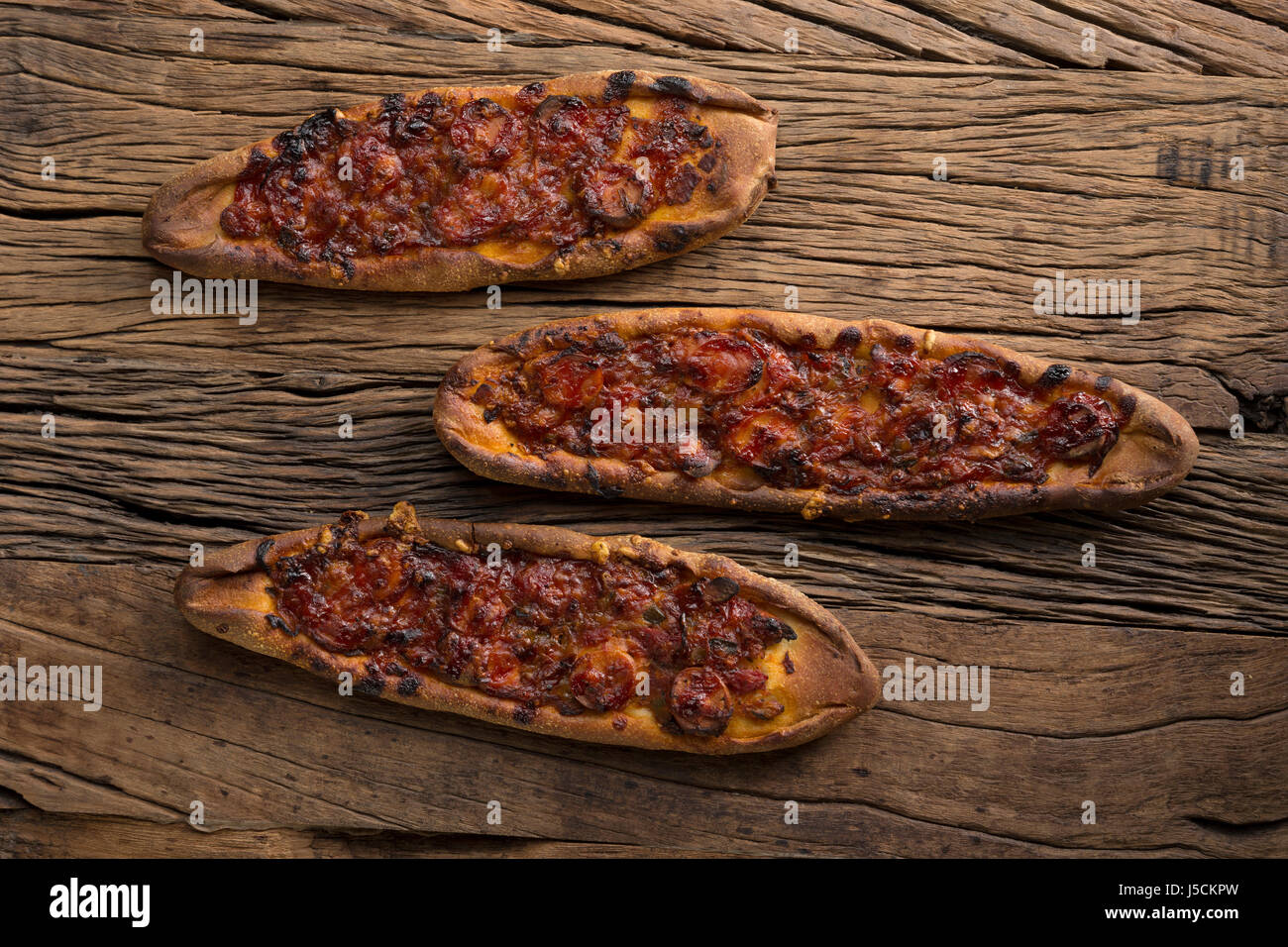 Turkish pide pizza sitting on a rustic wooden table. Stock Photo
