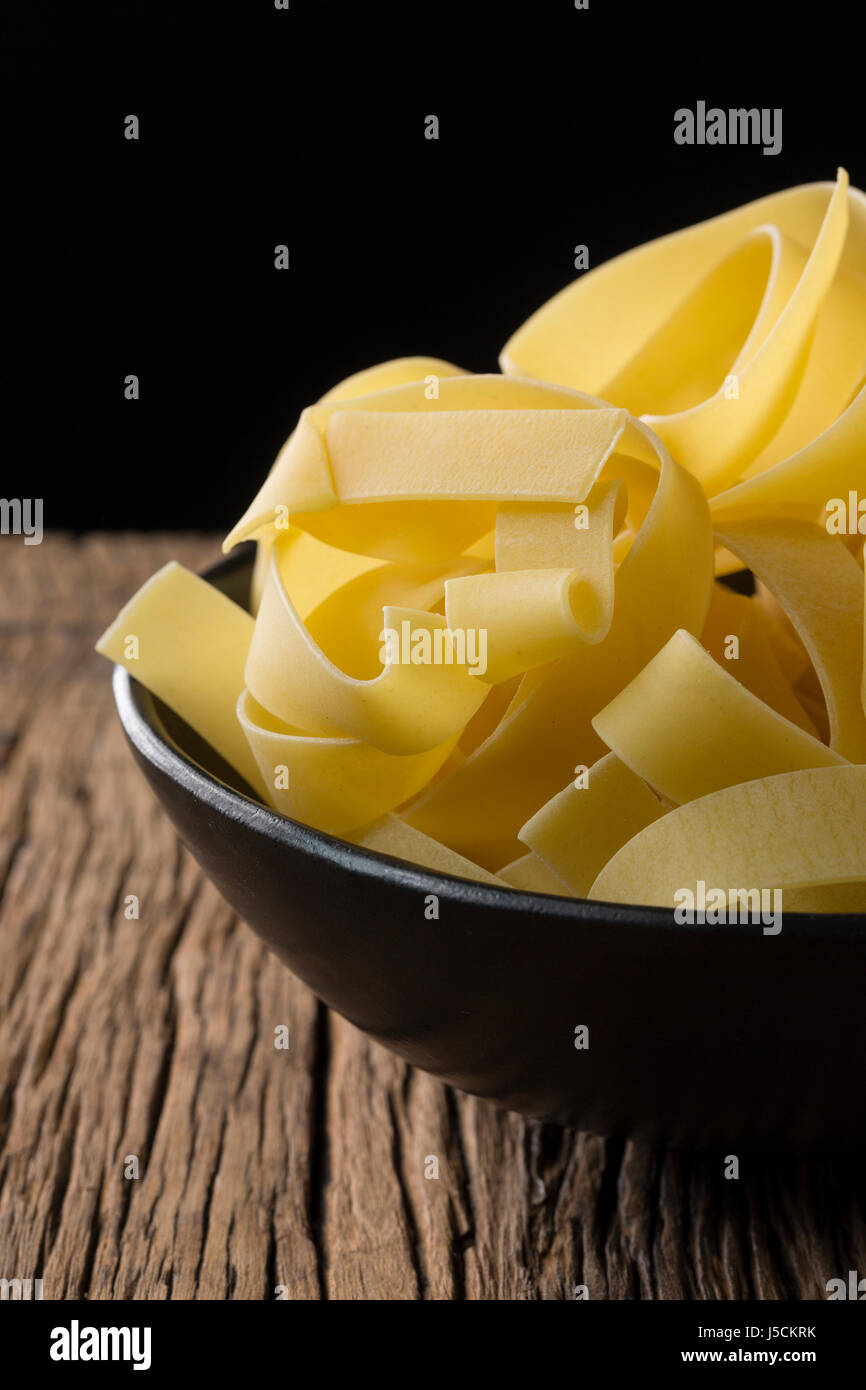 A bowl of dry pasta sitting on a rustic wooden table. Stock Photo