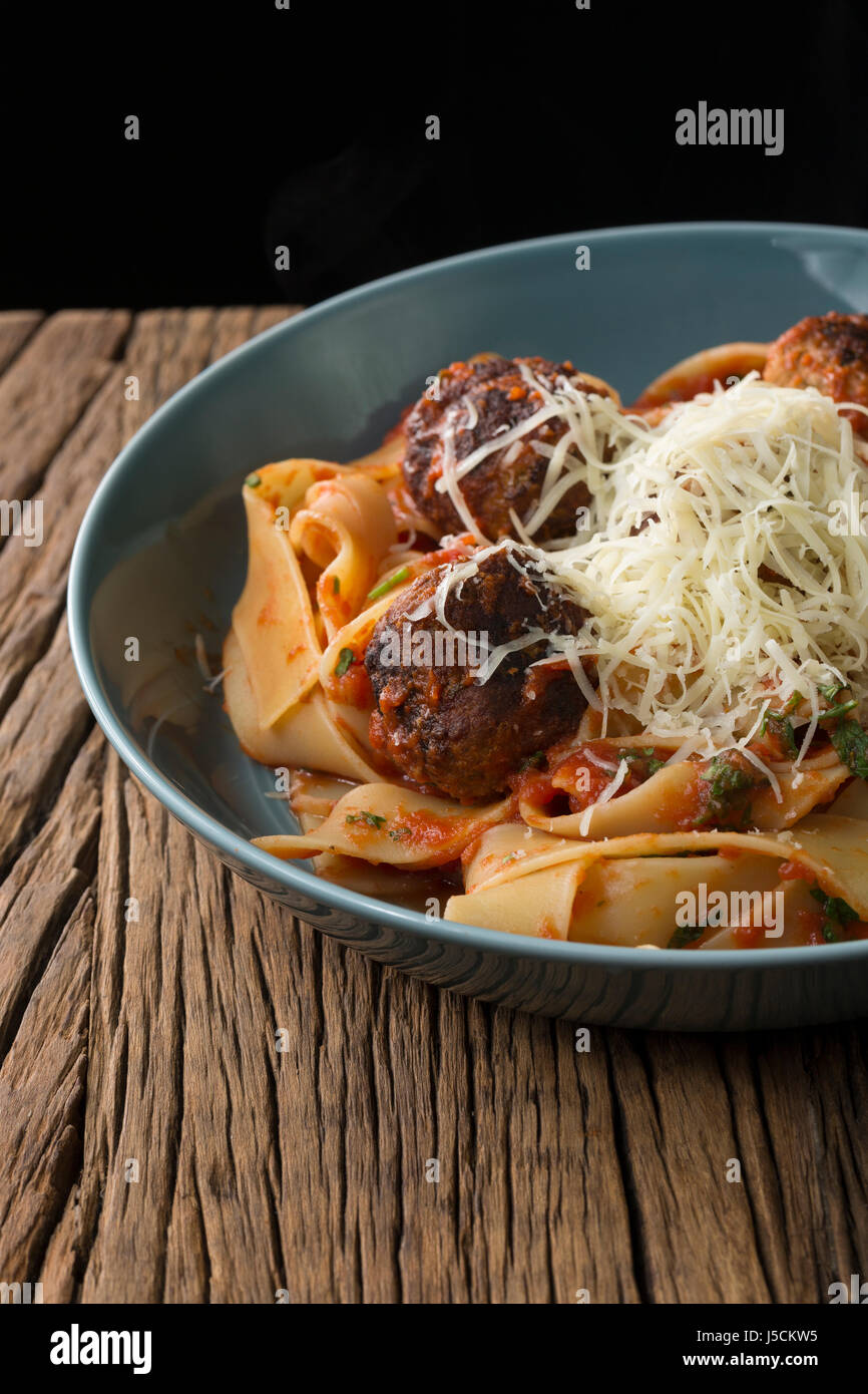 Italian meat balls with pasta, tomato sauce and Parmesan cheese. Sitting on a rustic wooden table. Stock Photo