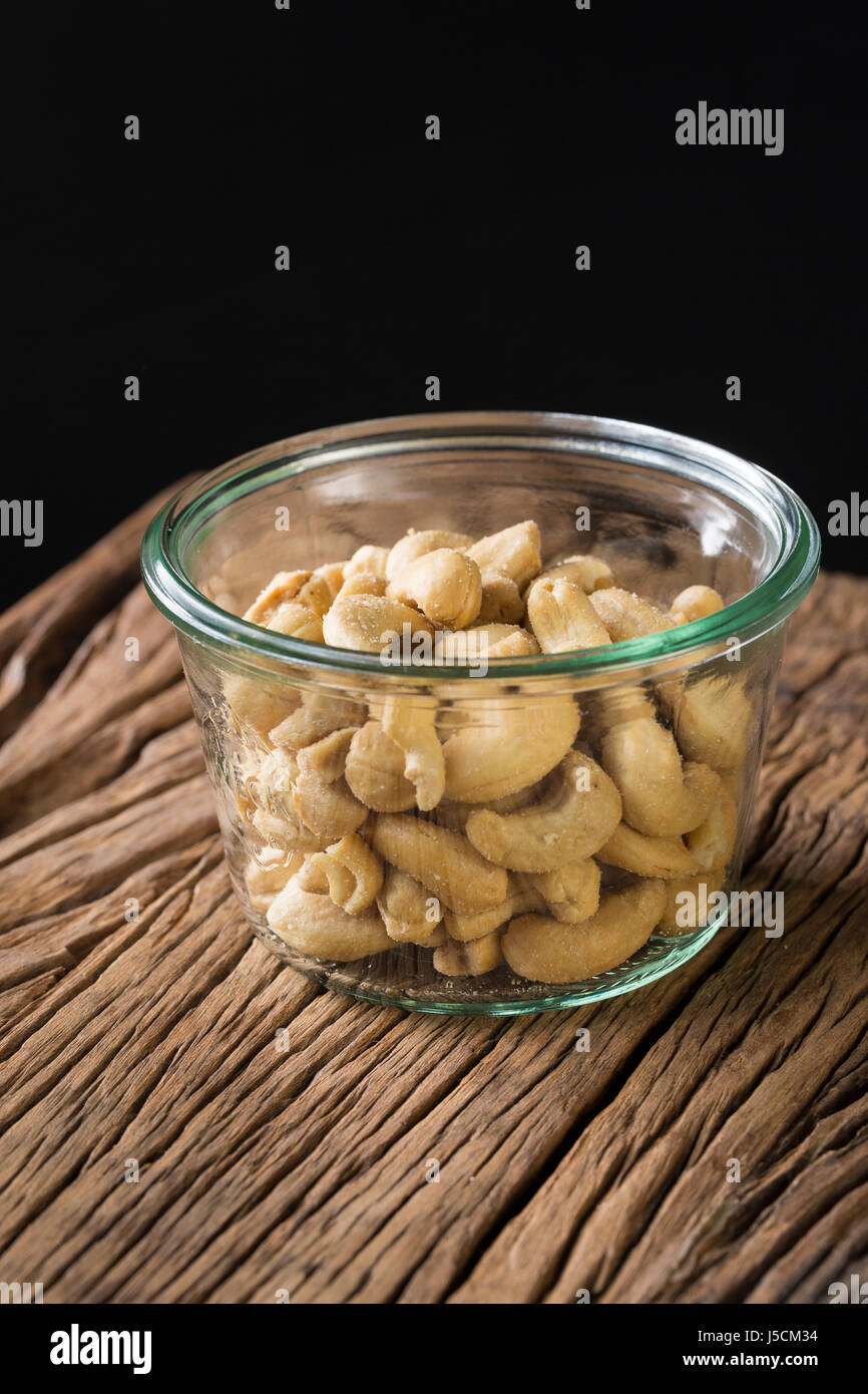 Glass bowl of cashew nuts on an old rustic wooden background. Modern styling. Stock Photo