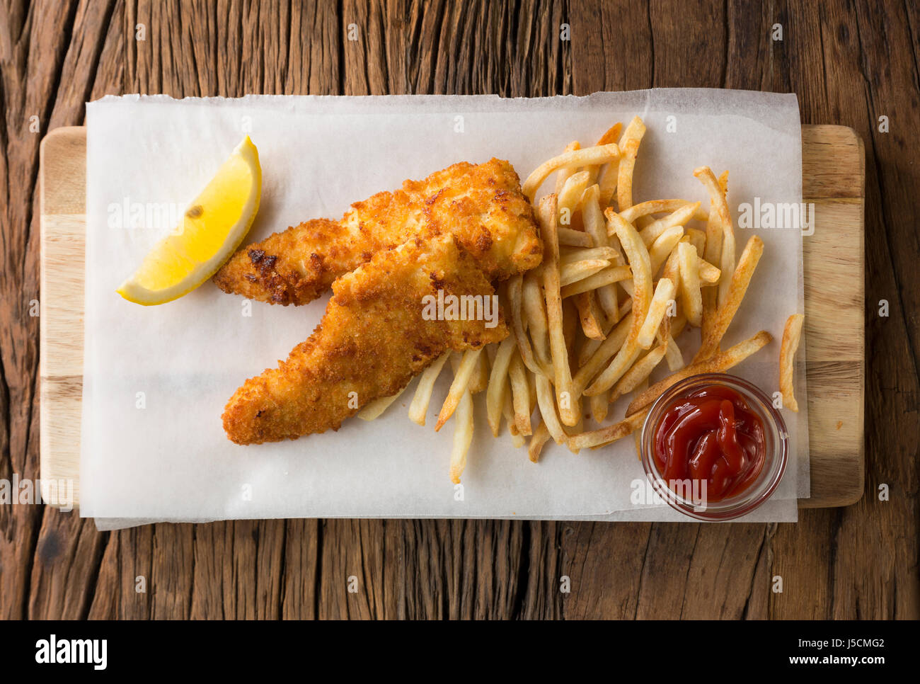 Freshly cooked fish and chips on a rustic wooden background. Gastropub style food. View from above. Stock Photo