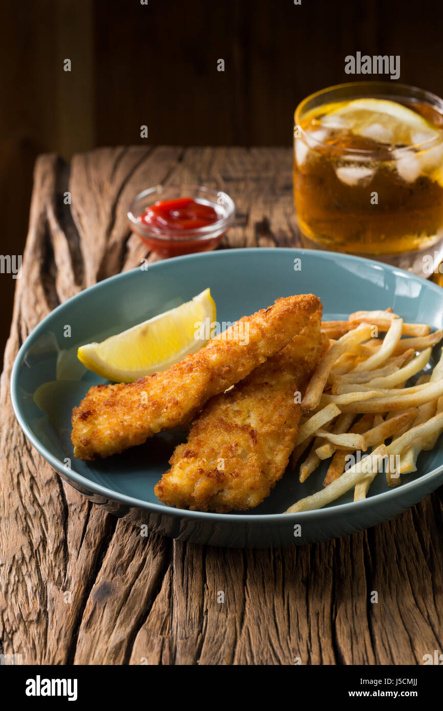 Freshly cooked fish and chips on a rustic wooden background. Gastropub style food. Stock Photo
