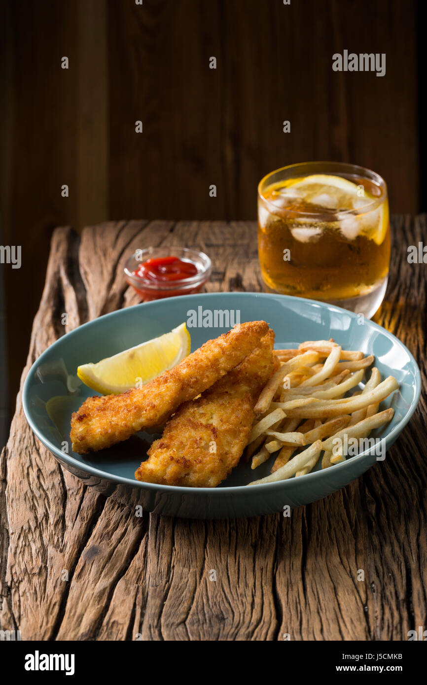 Freshly cooked fish and chips on a rustic wooden background. Gastropub style food. Stock Photo
