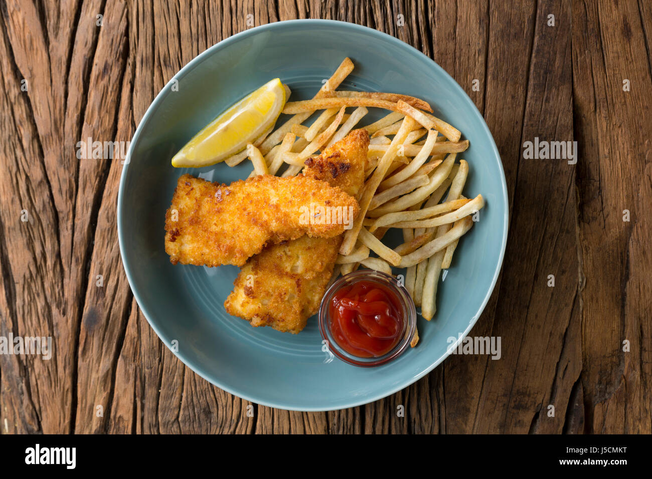 Freshly cooked fish and chips on a rustic wooden background. Gastropub style food. View from above. Stock Photo