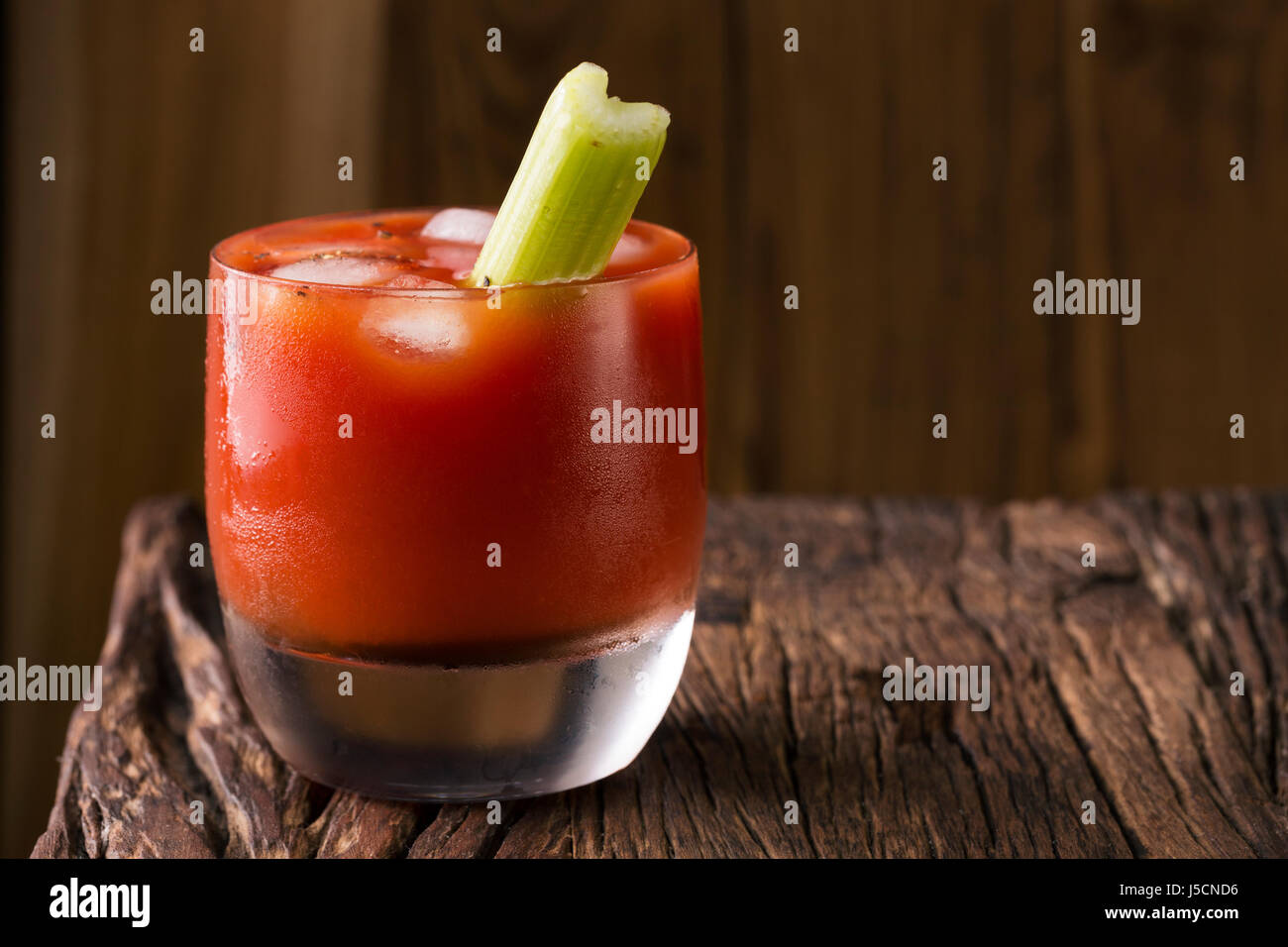 A bloody mary cocktail sitting on a rustic wooden bar. Stock Photo