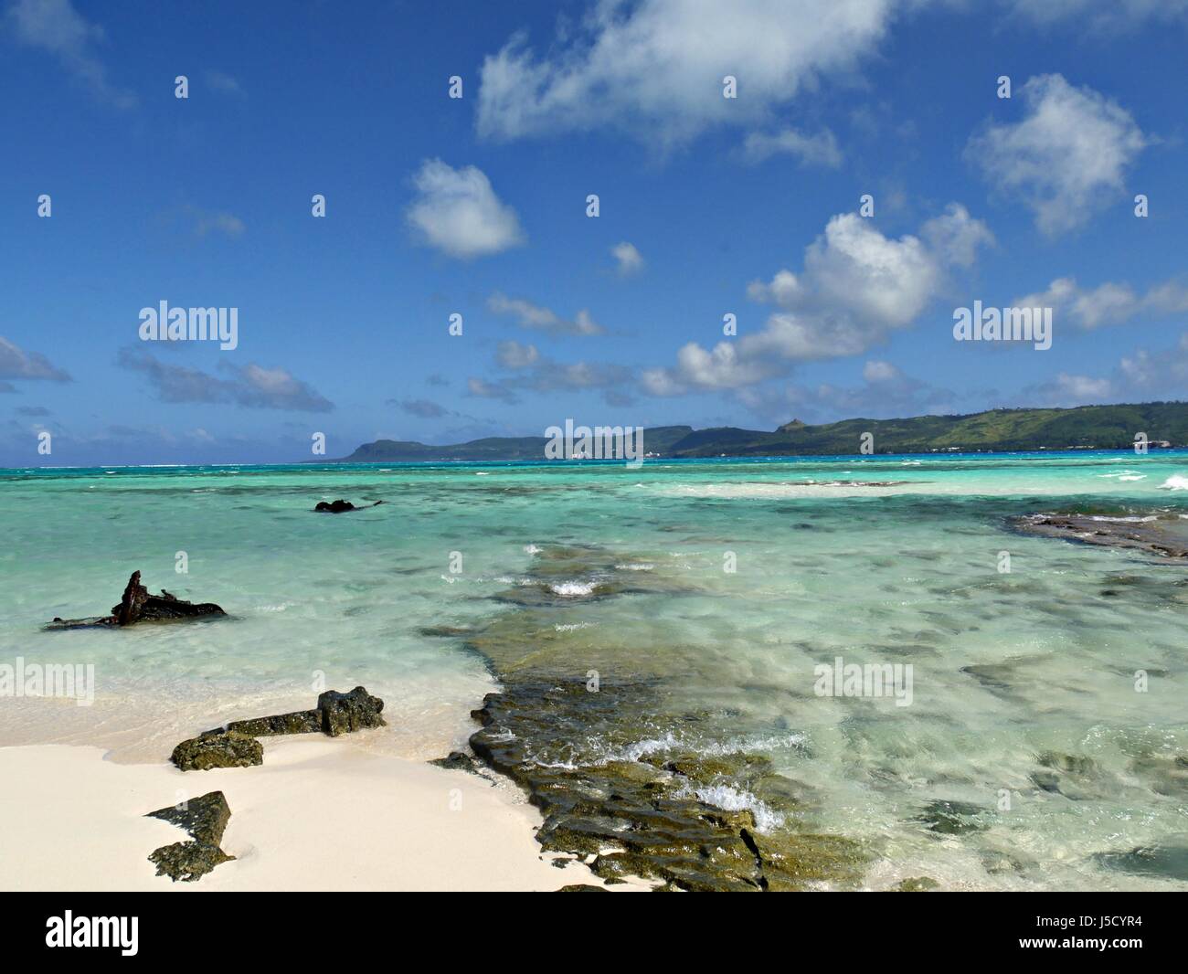 Crystal clear water rolls into the white sandy beaches and corals of Managaha Island Stock Photo