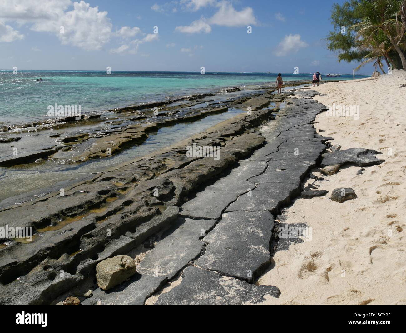 Saipan, USA- October 2016: Corals and rocks border the soft white sands and pristine, clear waters at the backside of Managaha Island. Stock Photo
