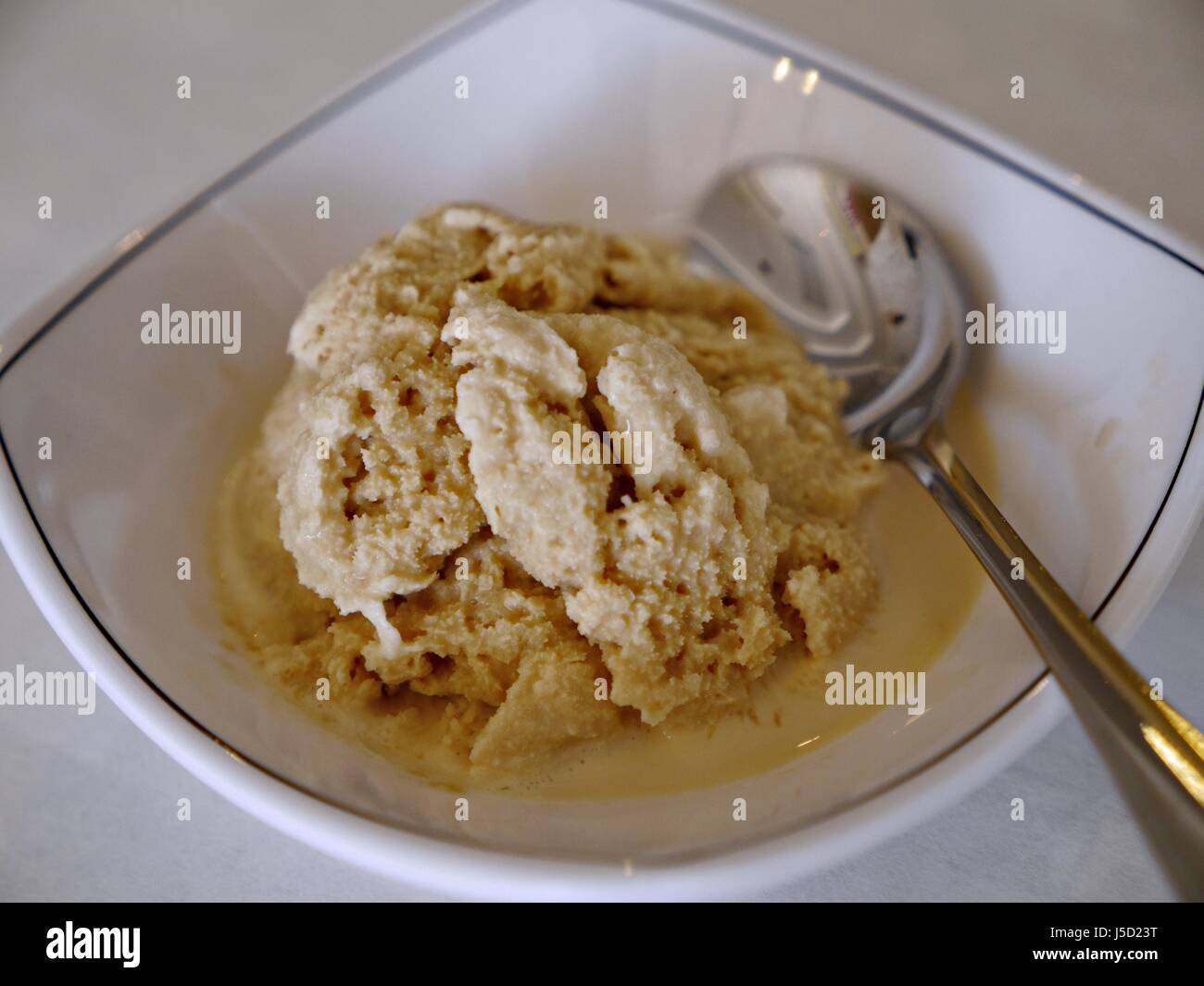 Top view of a scoop of melting vanilla ice cream served in a white bowl ...