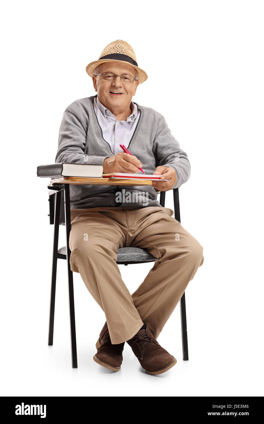 Mature man in a school chair taking notes and looking at the camera isolated on white background Stock Photo