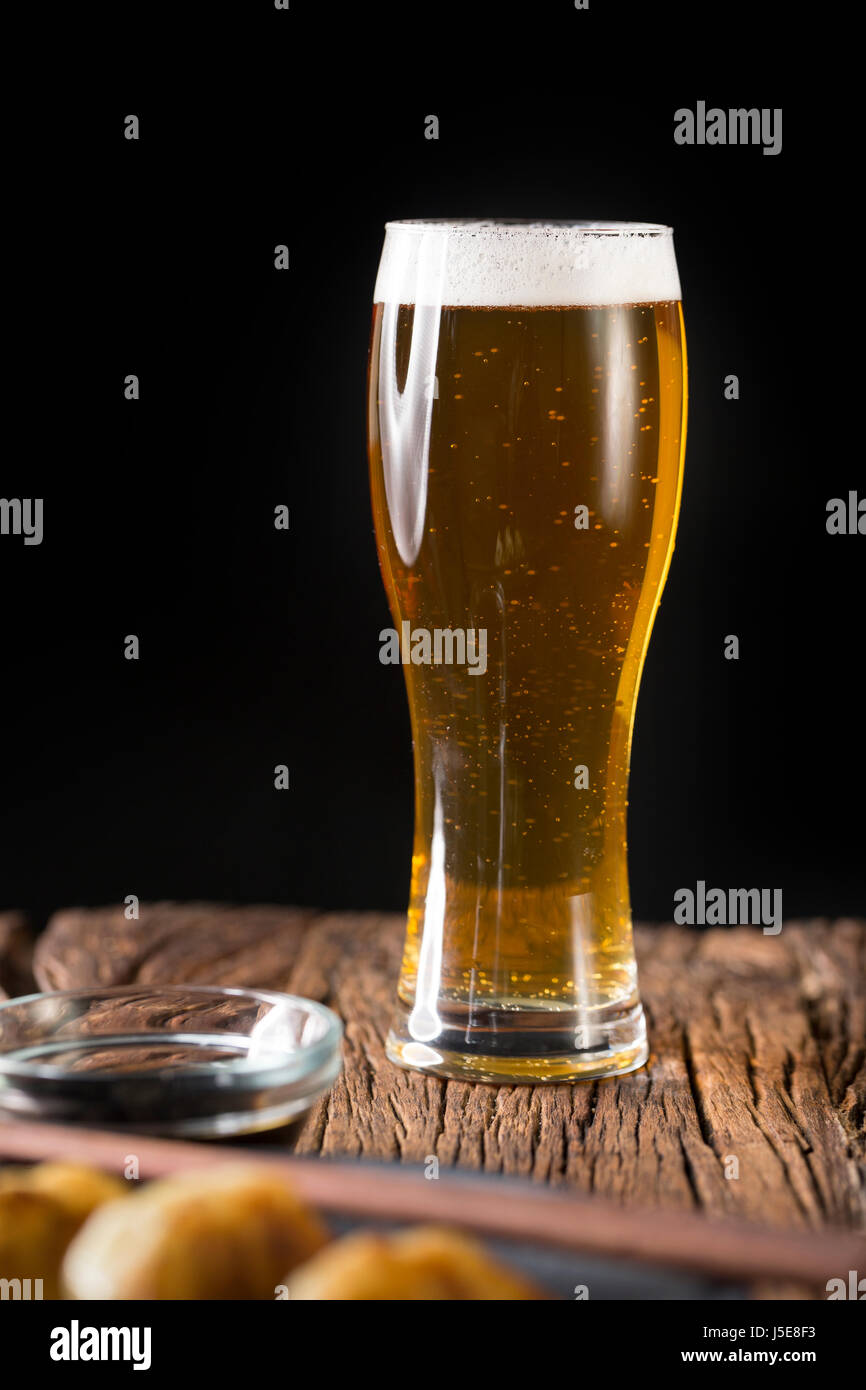A pint of Craft Beer sitting on a rustic wooden bar. Handcrafted microbrewery ale. Stock Photo