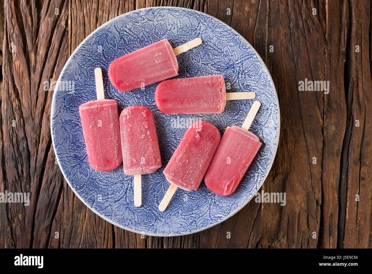 Homemade Raspberry and vanilla ice pops on a rustic wood background. Berry icecream popsicles. Summer food. Stock Photo