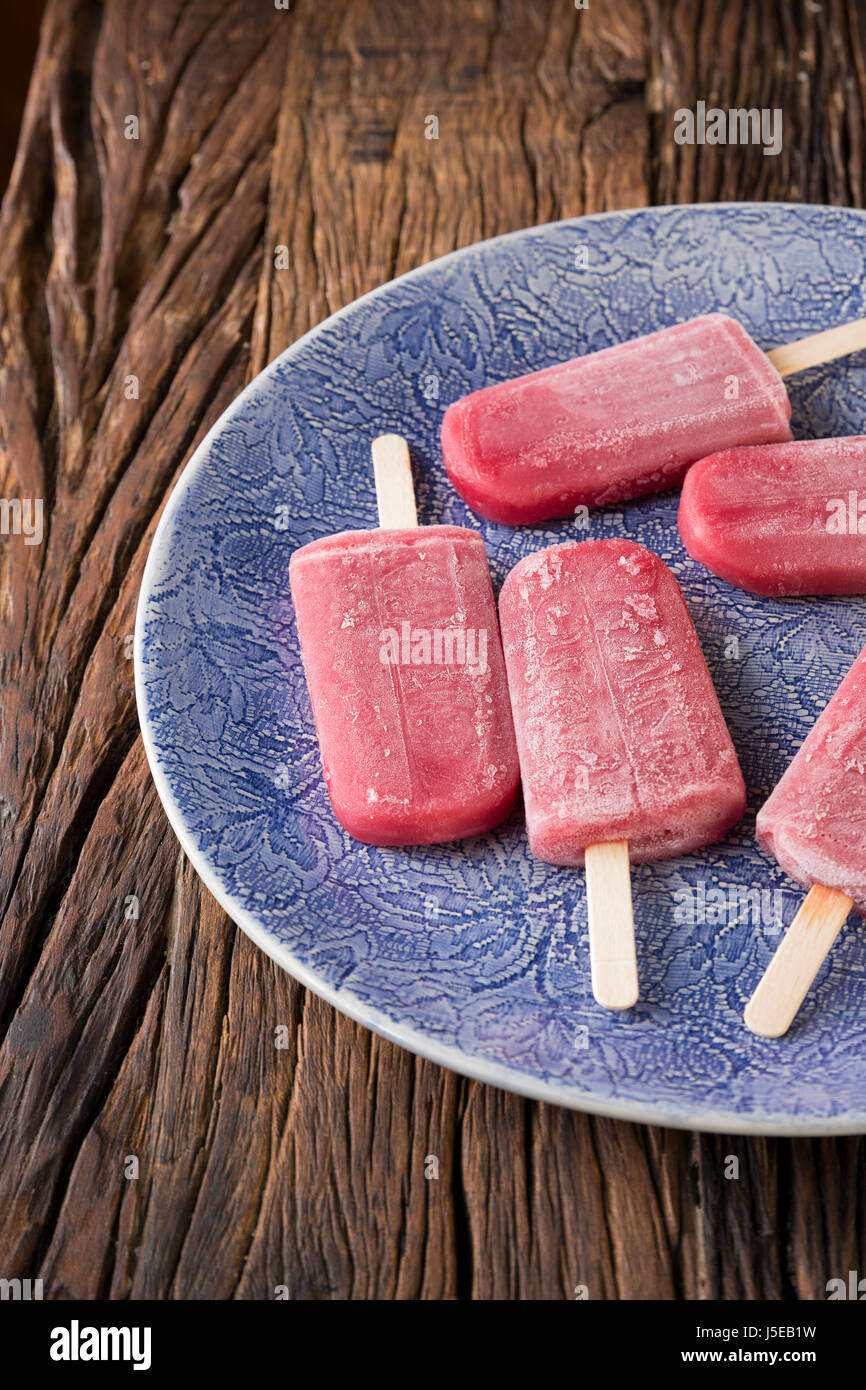 Homemade Raspberry and vanilla ice pops on a rustic wood background. Berry icecream popsicles. Summer food. Stock Photo