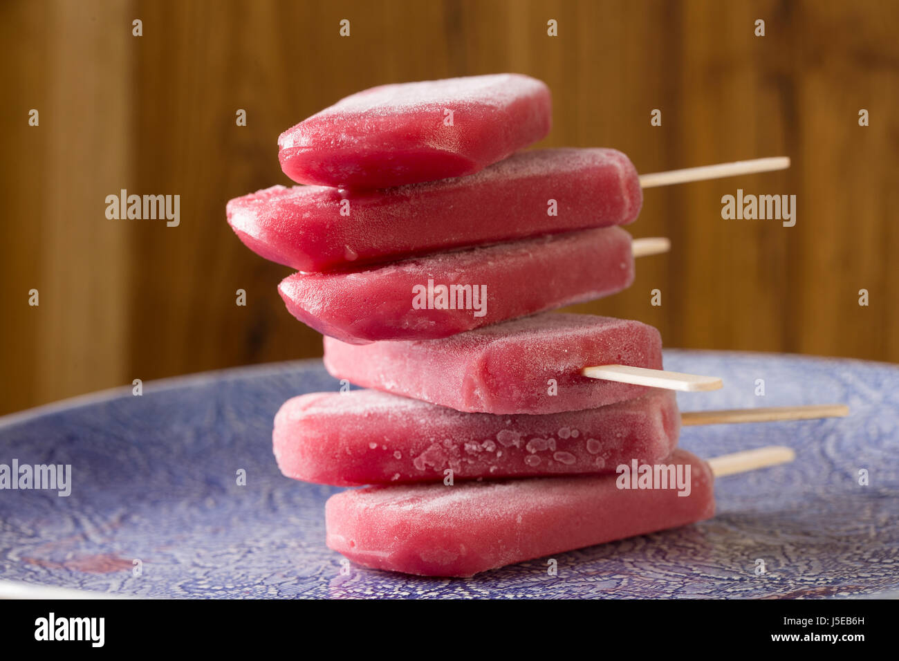 Homemade Raspberry and vanilla ice pops on a rustic wood background. Berry icecream popsicle. Summer food. Stock Photo
