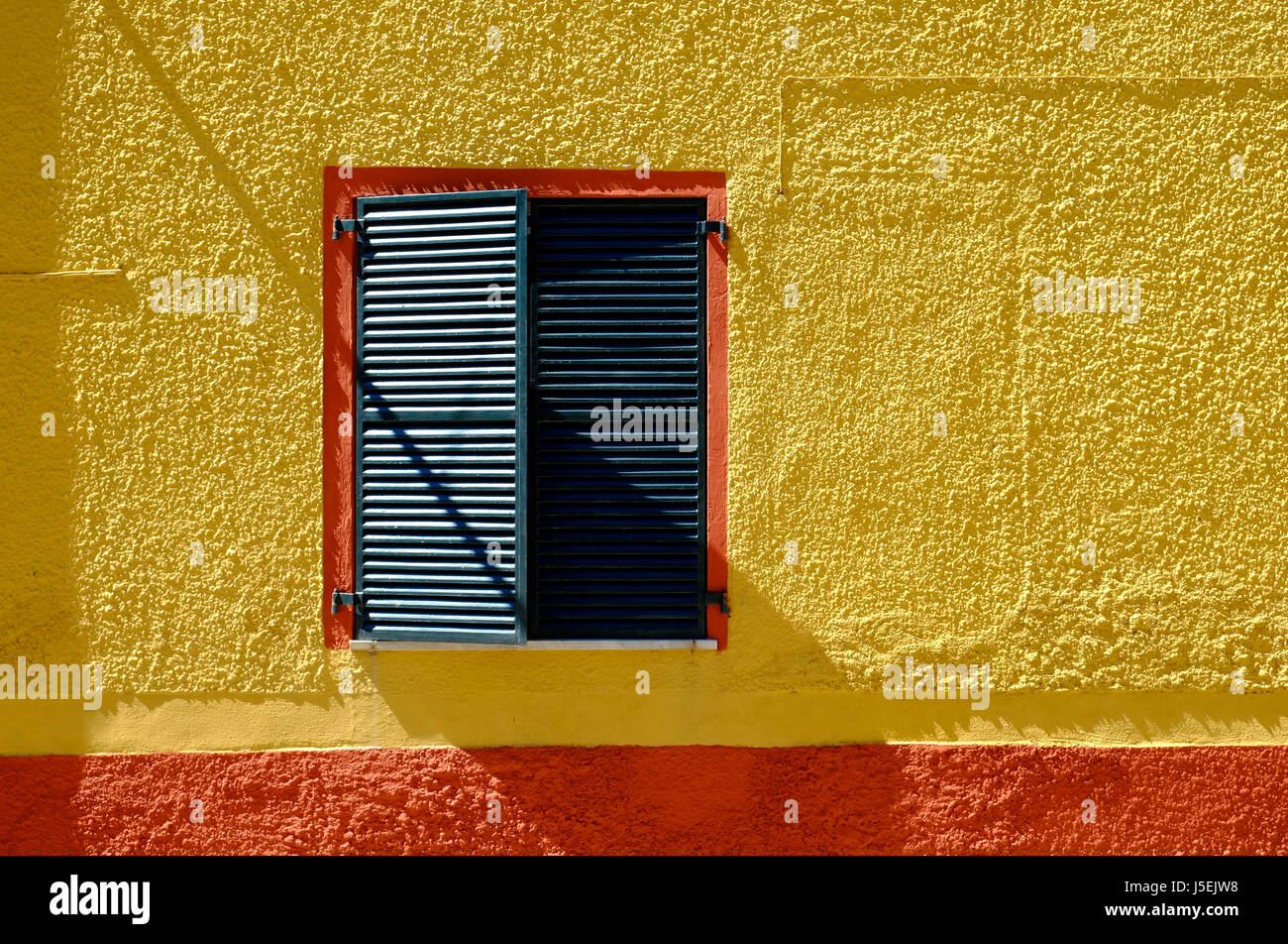 yellow painted house wall with green shutters, sardinia, italy Stock Photo