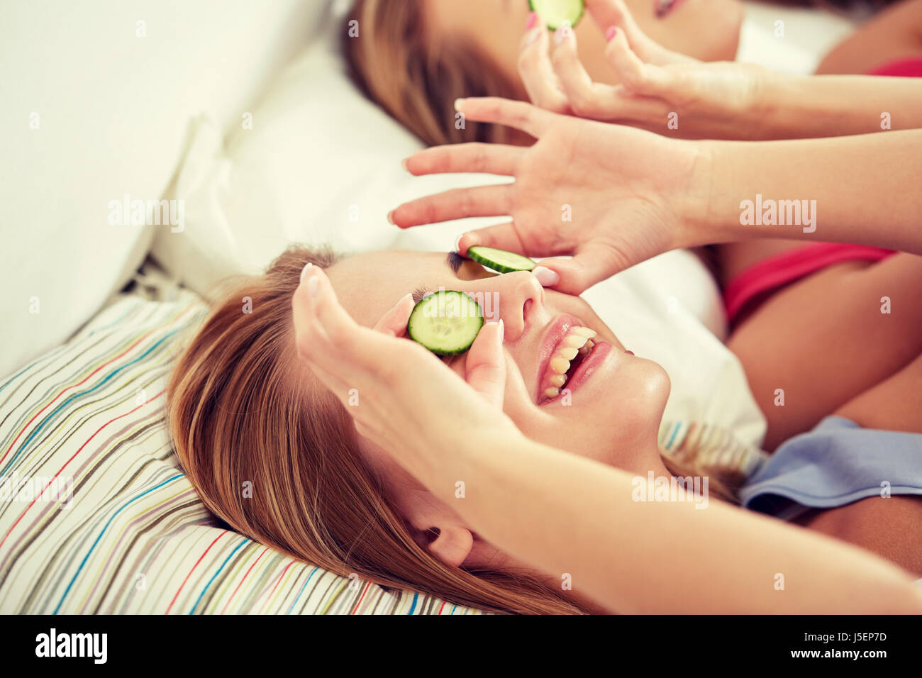 happy young women with cucumber mask lying in bed Stock Photo