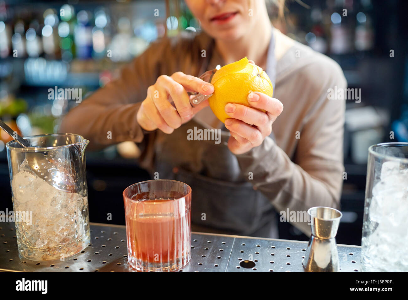 bartender peels orange peel for cocktail at bar Stock Photo Alamy