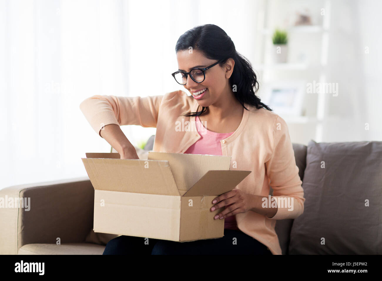 happy young indian woman with parcel box at home Stock Photo