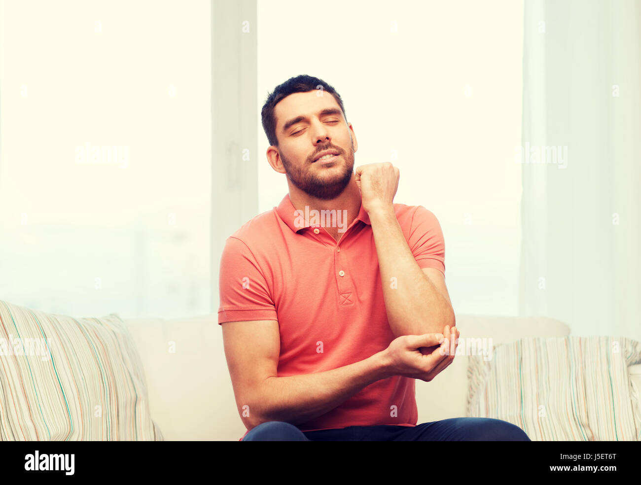 unhappy man suffering from pain in hand at home Stock Photo - Alamy