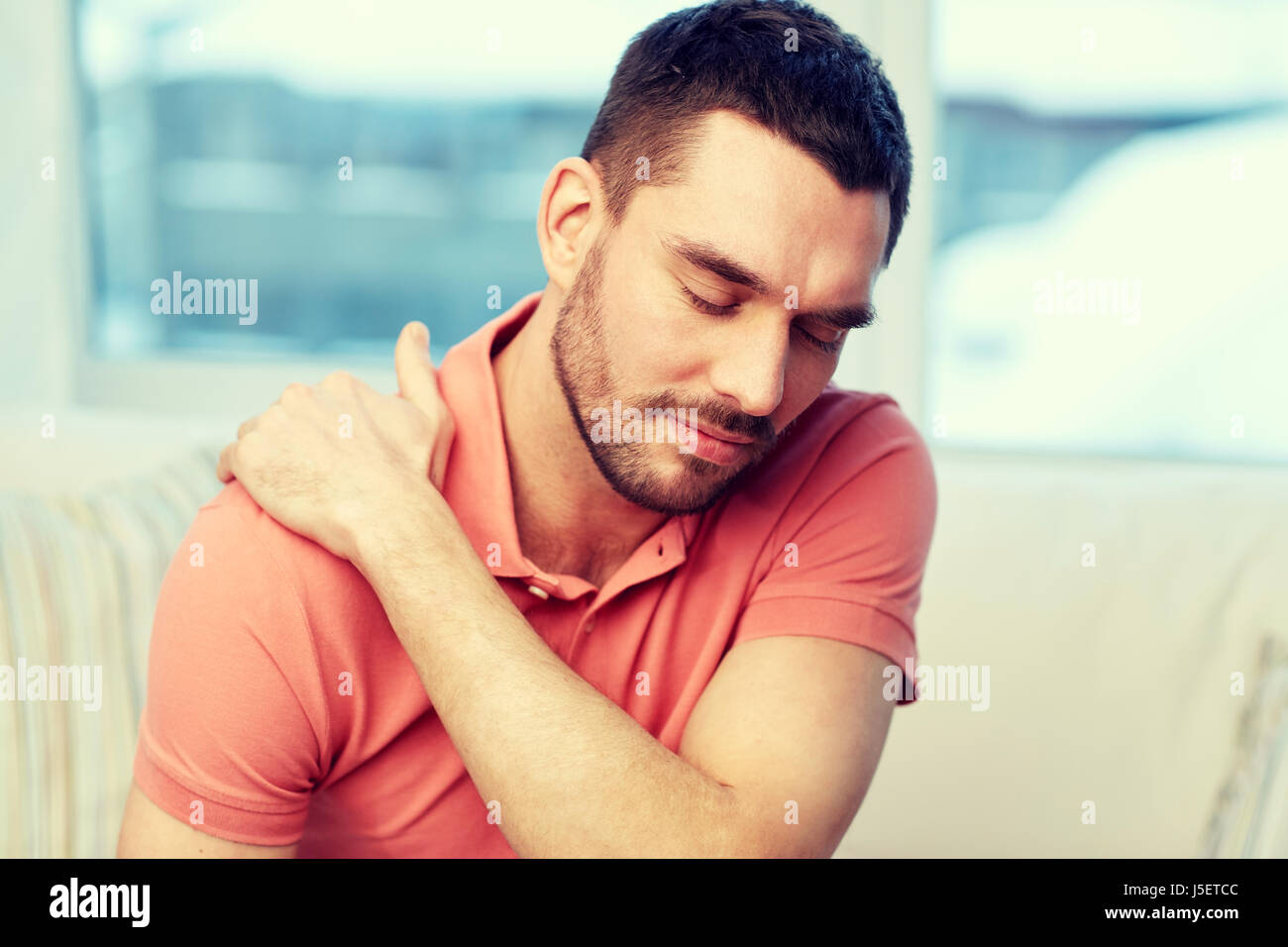 unhappy man suffering from neck pain at home Stock Photo - Alamy