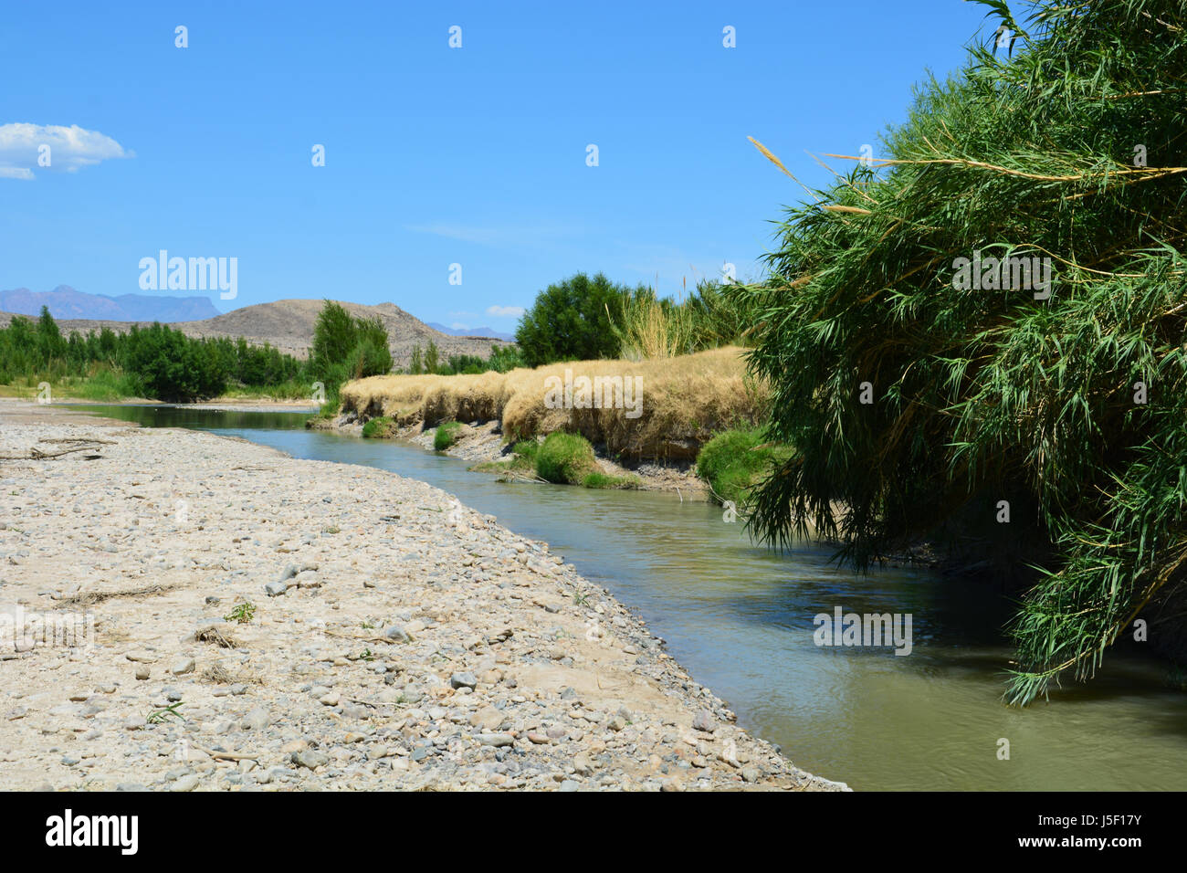 Low water in the Rio Grande leaves only a narrow channel in the riverbed as it emerges from the Santa Elena Canyon at Big Bend National Park Stock Photo