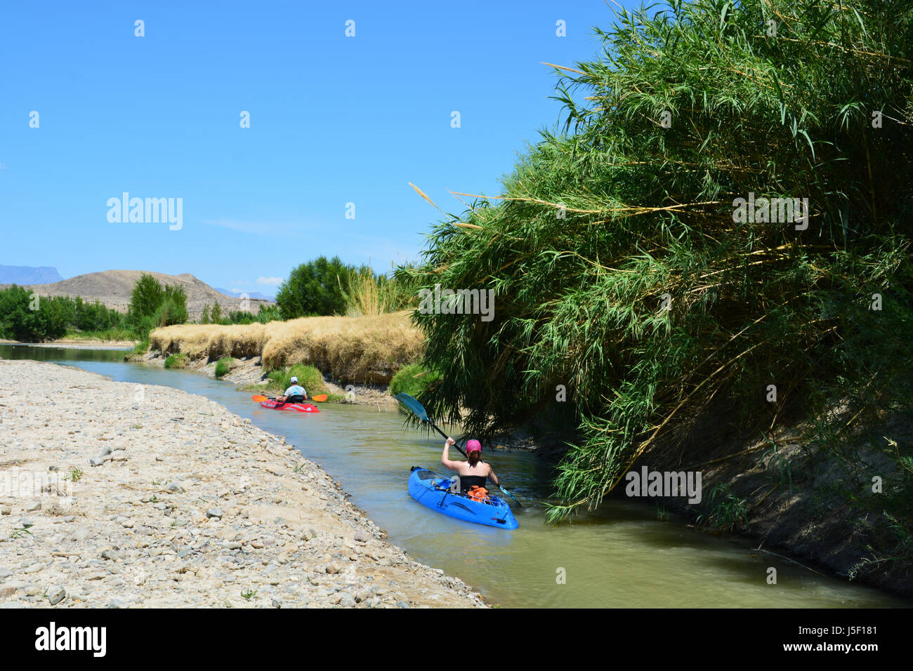 Kayaks navigate a narrow channel in the low waters of the Rio Grande as it exits Santa Elena Canyon at Big Bend National Park Stock Photo