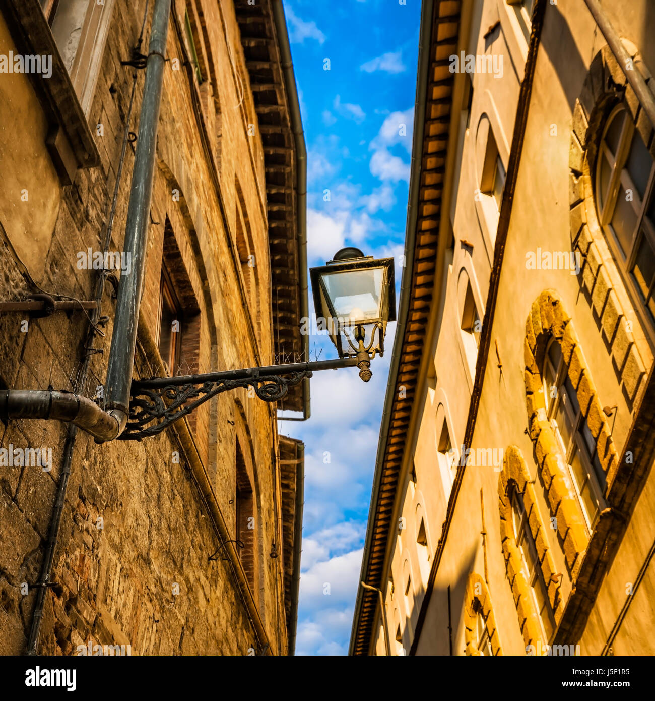 Tuscany urban abstract. Street lamp, red yellow orange traditional house facades and sky background. Bottom view Stock Photo