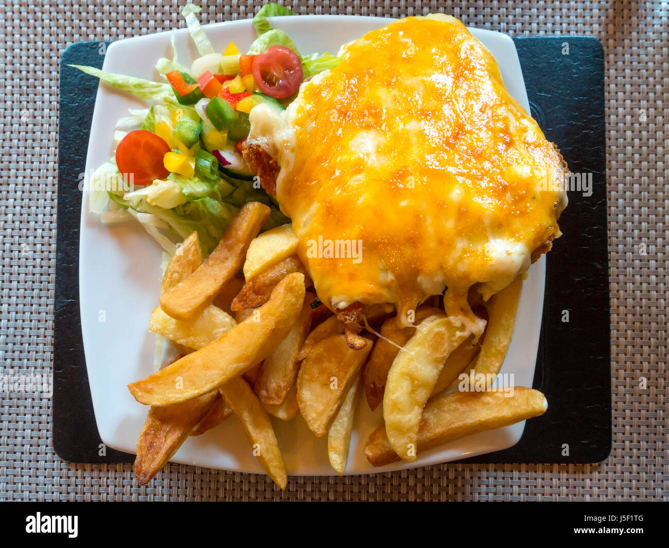 Chicken Parmesan or ”Parmo” a popular dish in North East England  deep-fried breaded chicken with béchamel sauce and melted cheese  chips and salad. Stock Photo