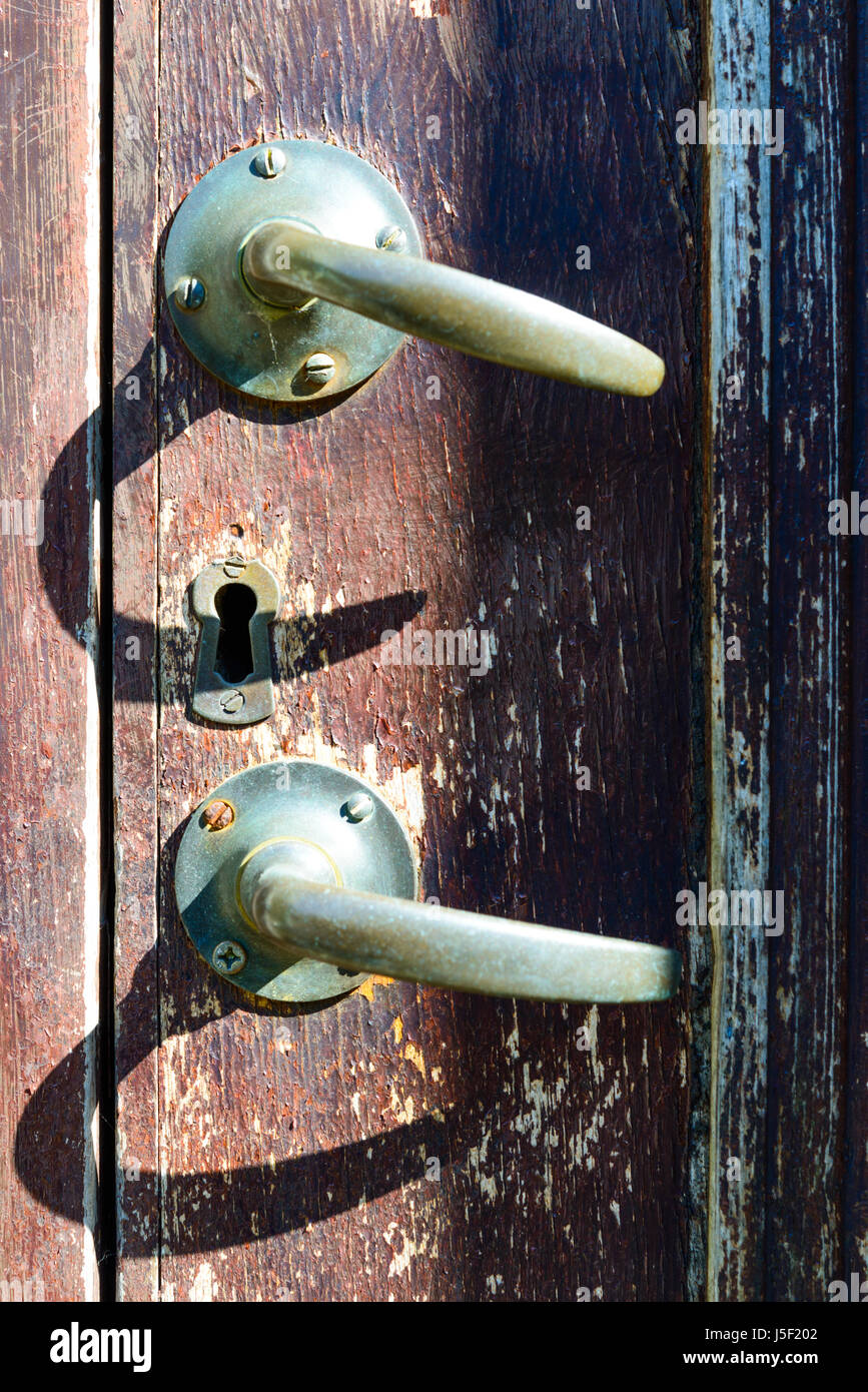 Two handles casting a strong shadow on a faded door. Stock Photo