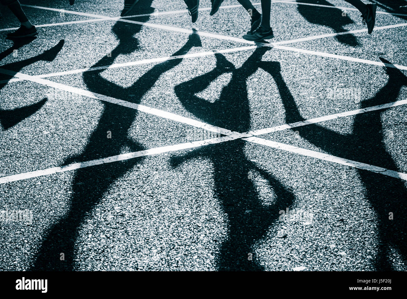 Runners shadows on road during city road race. Stock Photo