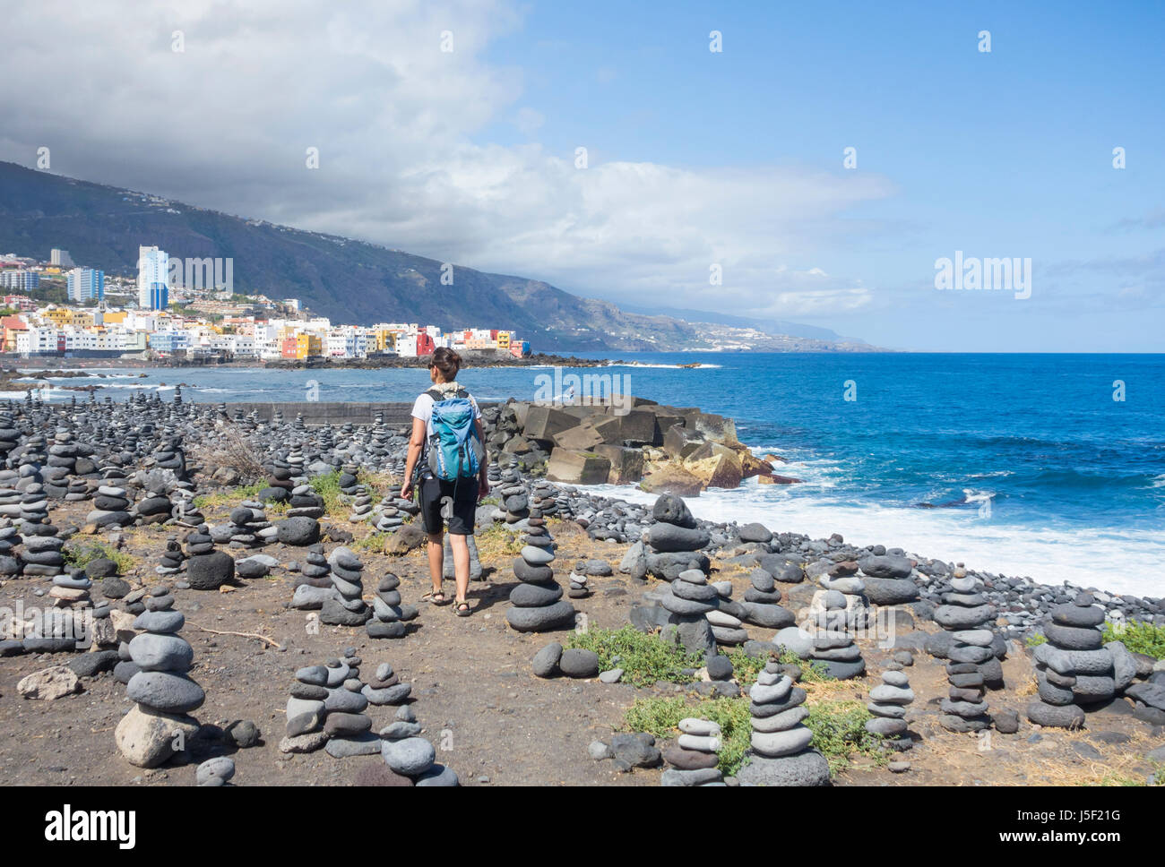 Puerto de La Cruz, Tenerife, Canary Islands, Spain. Female hiker on coastal footpath through stacks of balanced stones. Stock Photo