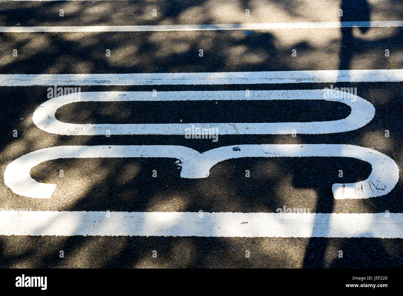 Shadows cast on 30 MPH speed limit numbers painted on to a road surface. Stock Photo