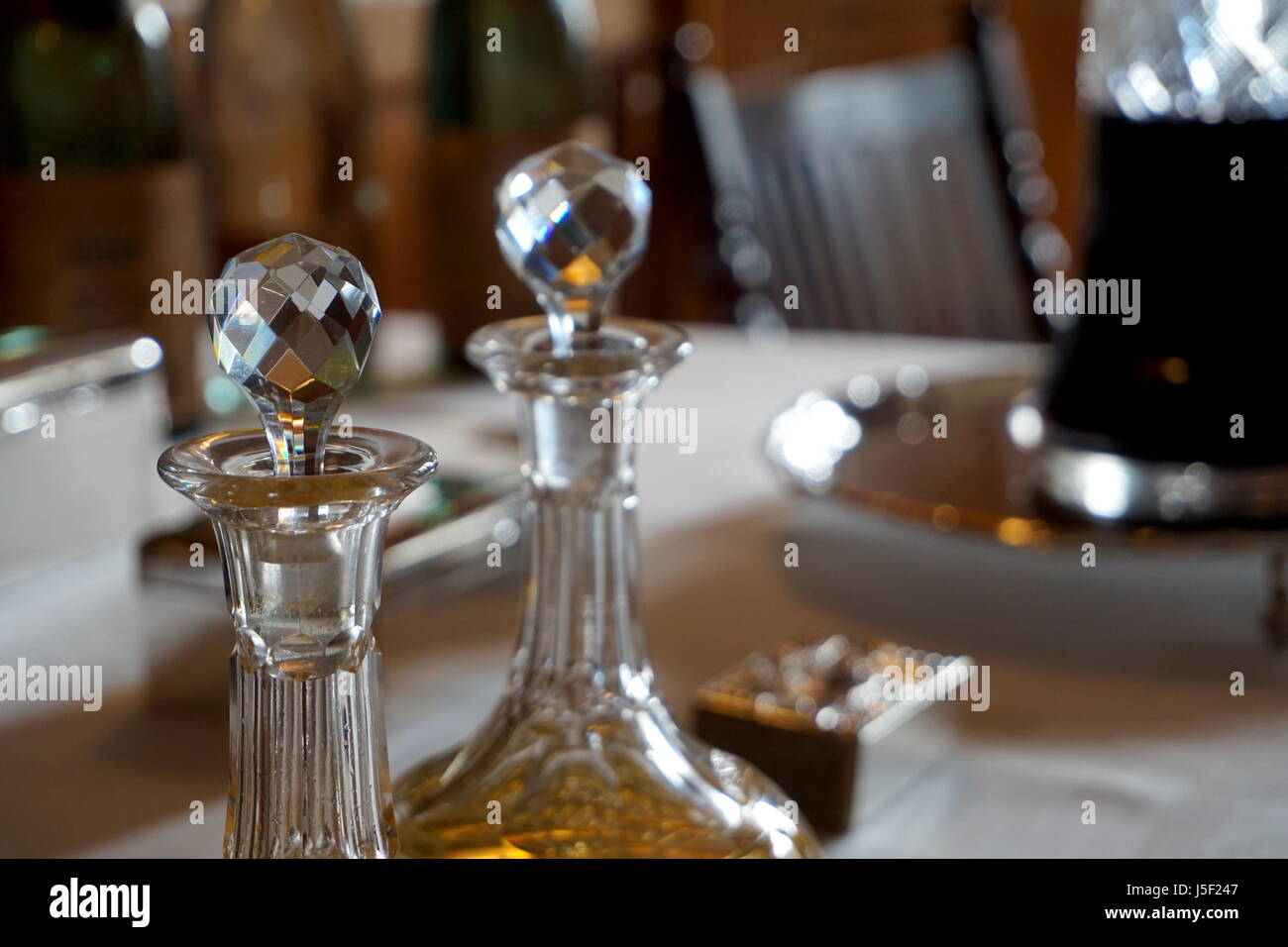 Old glass wine and spirit decanters on an ornate table in natural daylight Stock Photo