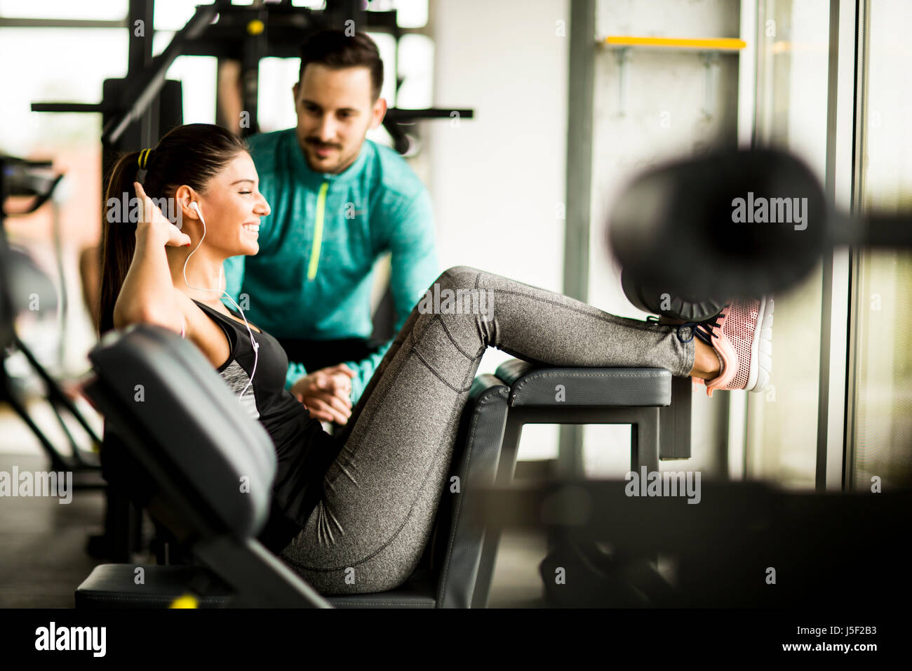 Young woman exercise in a gym with the help of her personal trainer ...