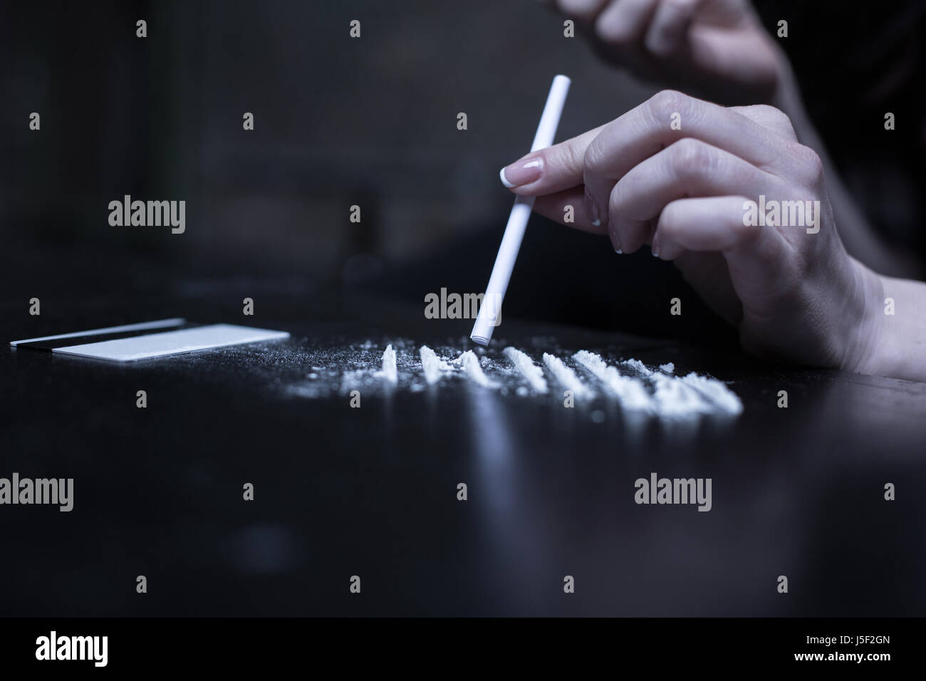 Heroin addict sniffing heroin lines in the darkness Stock Photo