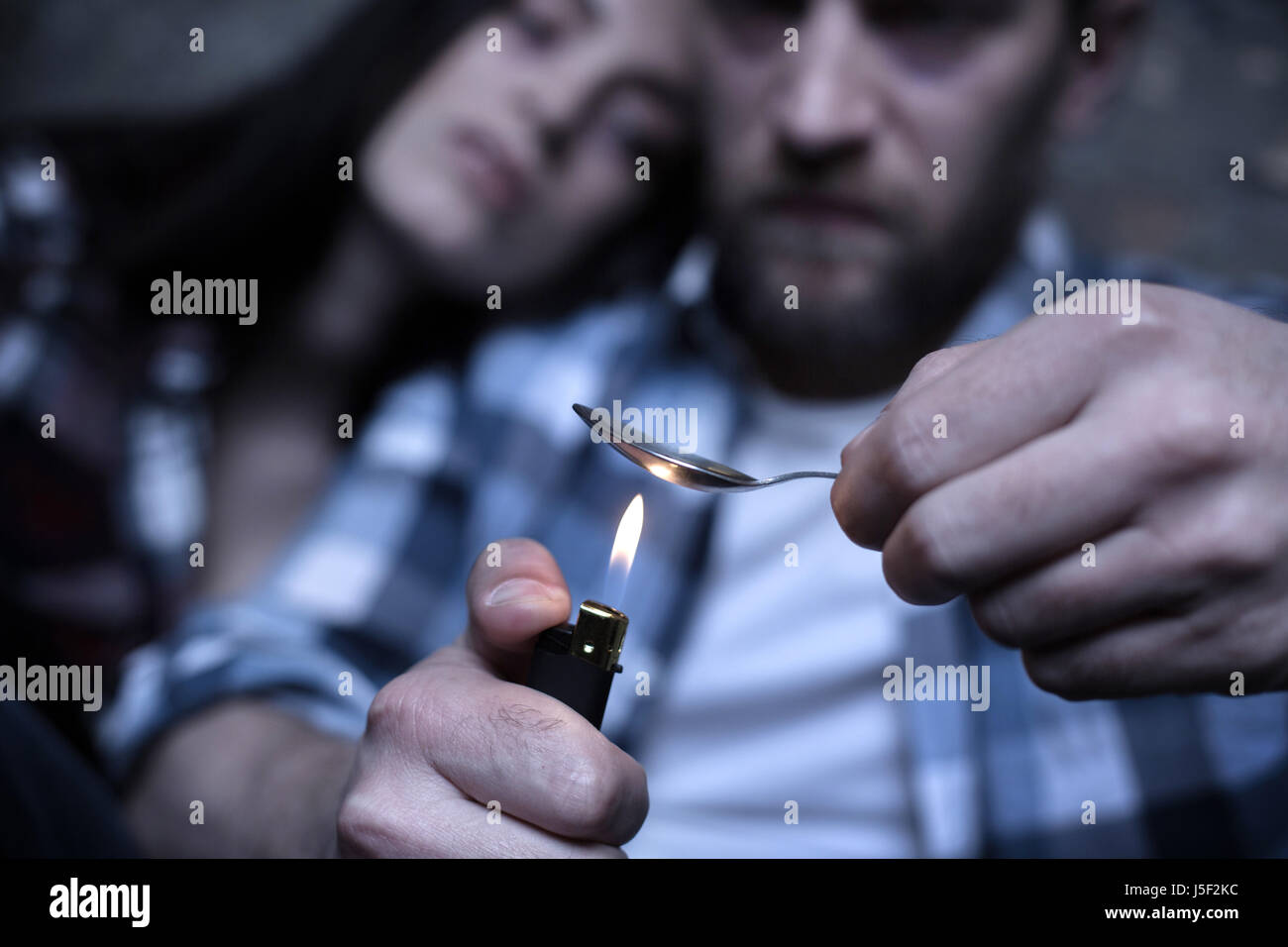 Stoned freaks heating heroin in the spoon outdoors Stock Photo