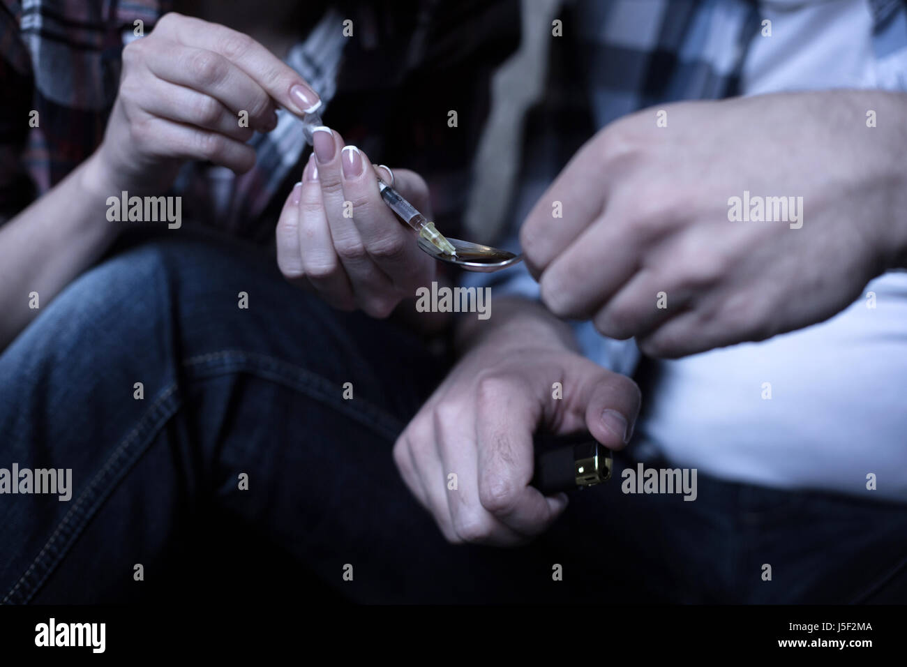 Young freaks heating drugs over the flame in the darkness Stock Photo