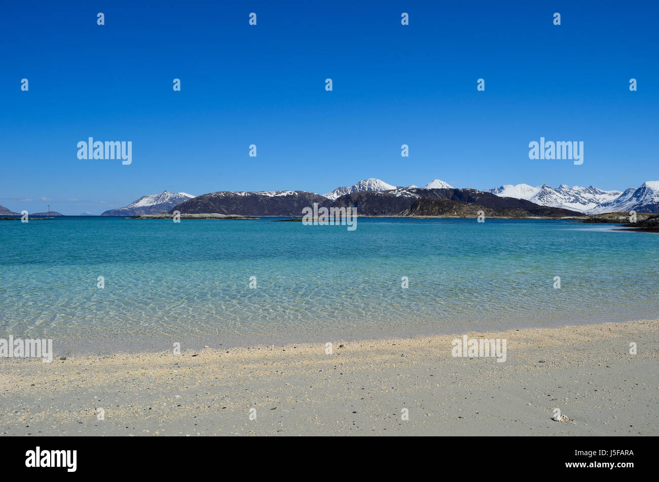majestic white springtime beach with snowy mountain islands in sea on ...
