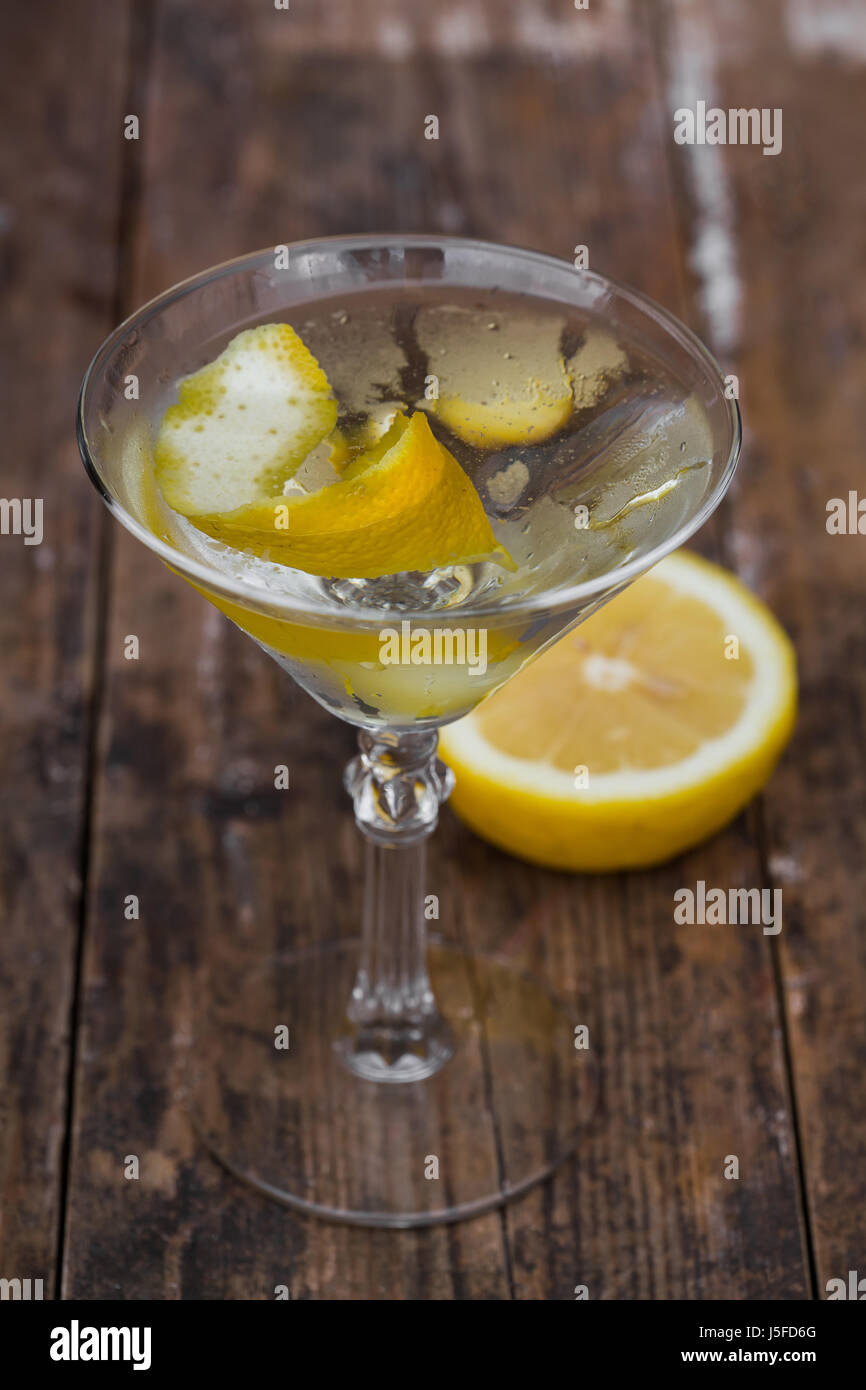 dirty martini chilled and garnished with a lemon twist on wooden table. Stock Photo