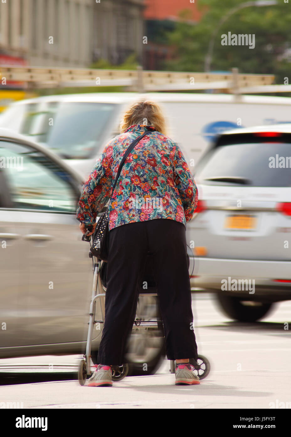 A frail elder women attempting to cross a crowded and busy dangerous street Stock Photo